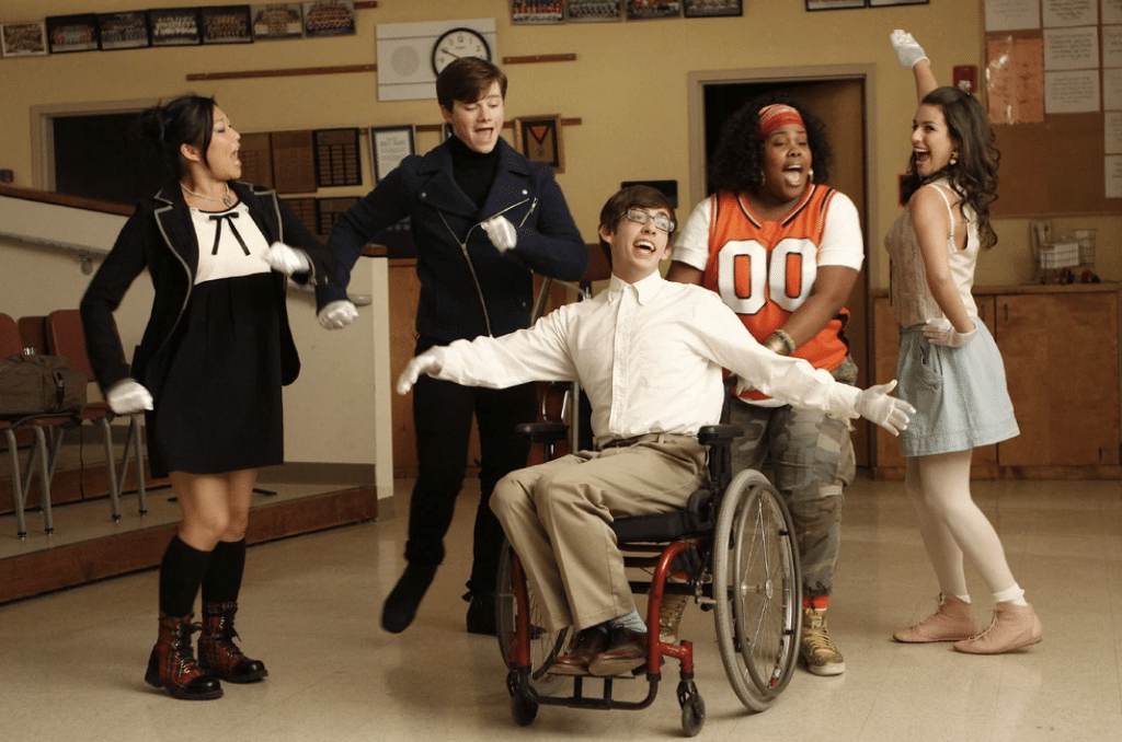 Scene from the pilot episode of Glee, featuring the New Directions glee club performing 'Sit Down, You’re Rockin' the Boat' in the choir room.
